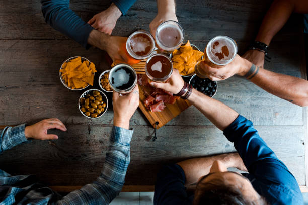 Top view of friends sitting at the table in the pub, drinking beer. Unrecognizable people. High angle view of table.