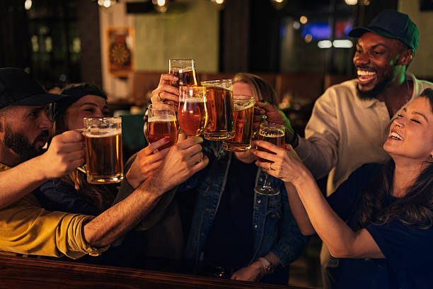 Cheerful multiracial friends toasting with beer glasses, enjoying a night out at the pub