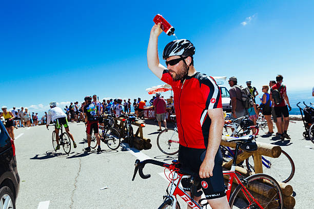 Sault, France - July 17, 2014: Male cyclist cooling himself by pouring water over his head at the summit finish of the climb on Mont Ventoux in the Provence region of France. A well known climb as a frequent stage on the Tour de France, it attracts thousands of cyclists every year, keen to match themselves against the steep gradients and achieve a personal goal.